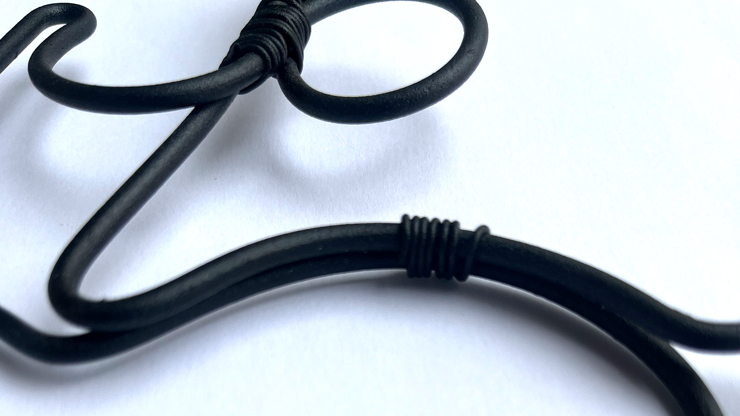 a close up image of black bent powder coated black steel wall art on white background with shadows