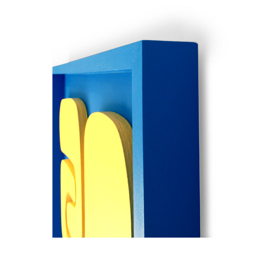 Discover the vibrant "Origin wall art" by Living Things Creative, showcasing interlocking abstract shapes in bright yellow against a blue rectangular frame. This textured piece, characterized by its curved and flowing lines, delivers a colourful and dynamic visual effect with a modern aesthetic.